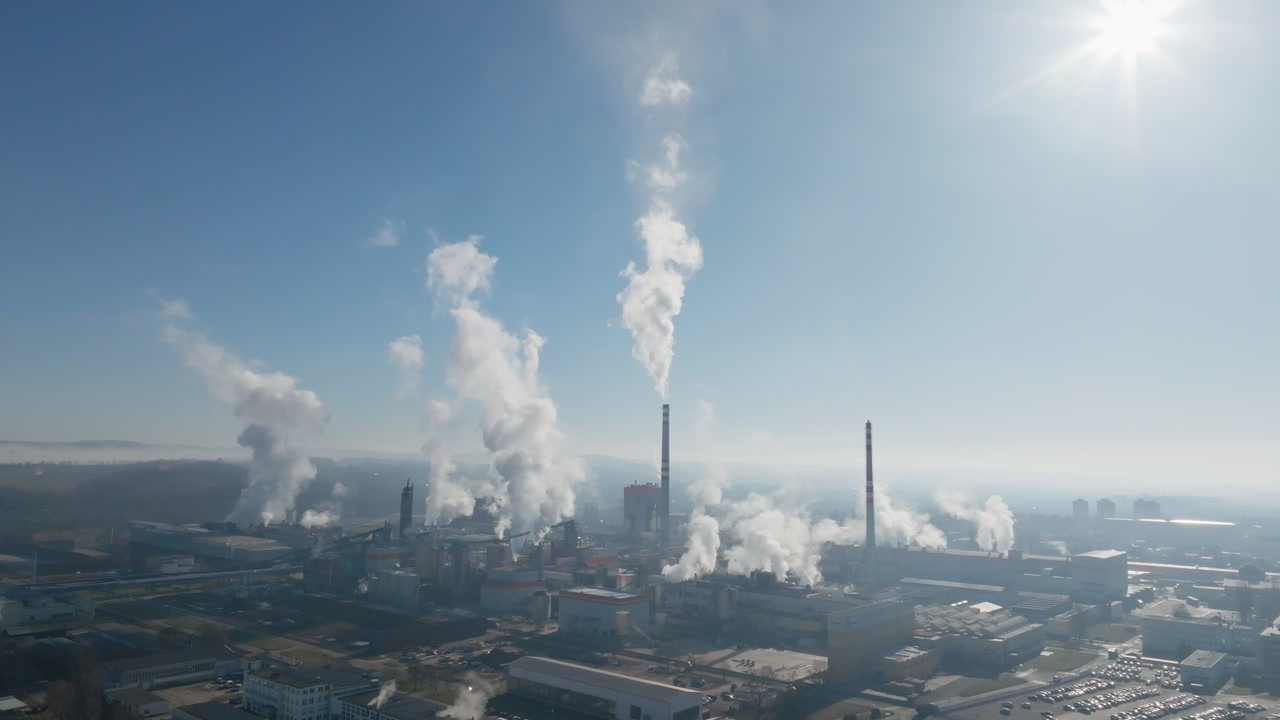 Wide aerial panorama showing treatment tanks and multiple steam plumes over the Štětí industrial complex, emphasizing scale and atmospheric haze.