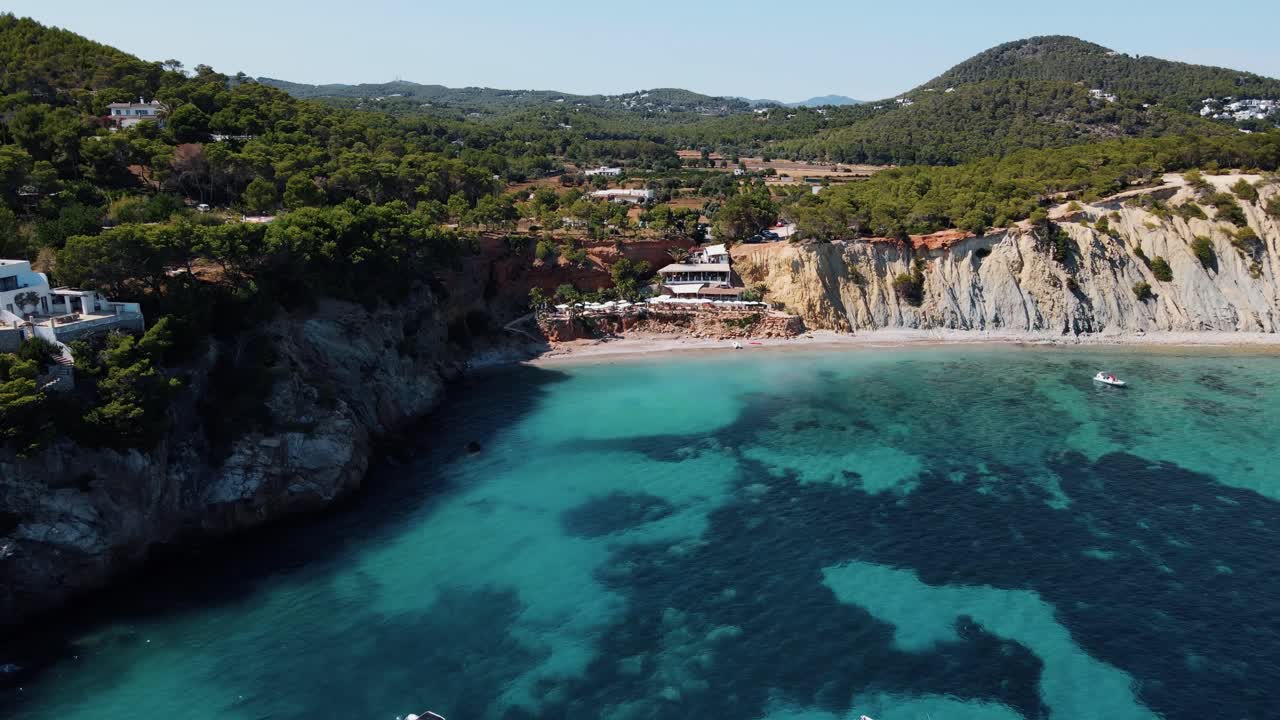 Filmisk droneoptagelse der flyver over det turkisblå havvand ved De Baleariske Øer med et luksuskrydstogtskib der sejler forbi, Spanien.