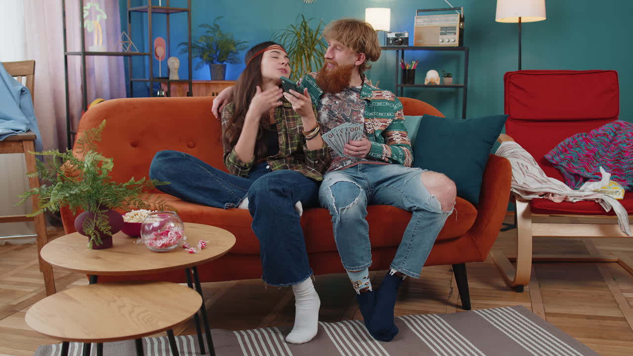 Smiling happy family couple man woman counting money cash use smartphone income saves lottery win