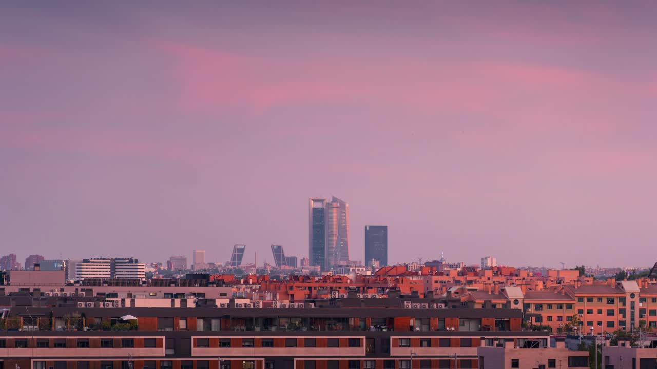 Timelapse do dia para a noite do horizonte de Madrid, visto de San Sebastián de los Reyes, apresentando a Área de Negócios Quatro Torres sob um pôr do sol colorido que se transforma numa vista noturna das luzes da cidade