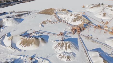 gravel quarry in winter, snowy piles, conveyor belts, aerial view, industrial scene