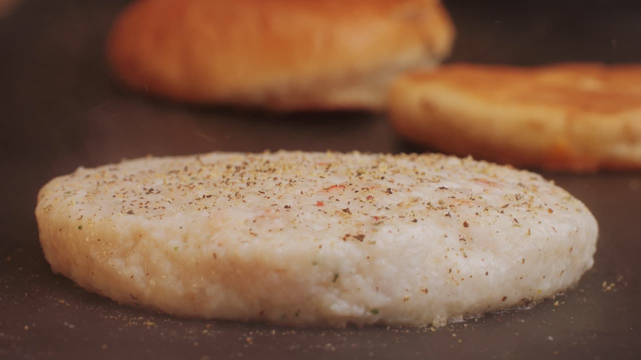 Cooking American fat smash burger on grill close-up. Chiken or fish cutlet smashing by burger press. The chef in kitchen of the restaurant making cutlets for burgers - smash burger beefsteak. Fast and street food concept. High quality 4k footage