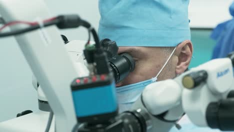 surgeon looking into the microscope at the eye of female patient at the operating room. doctor using microscope during eye surgery process, treatment of cataract and diopter correction.