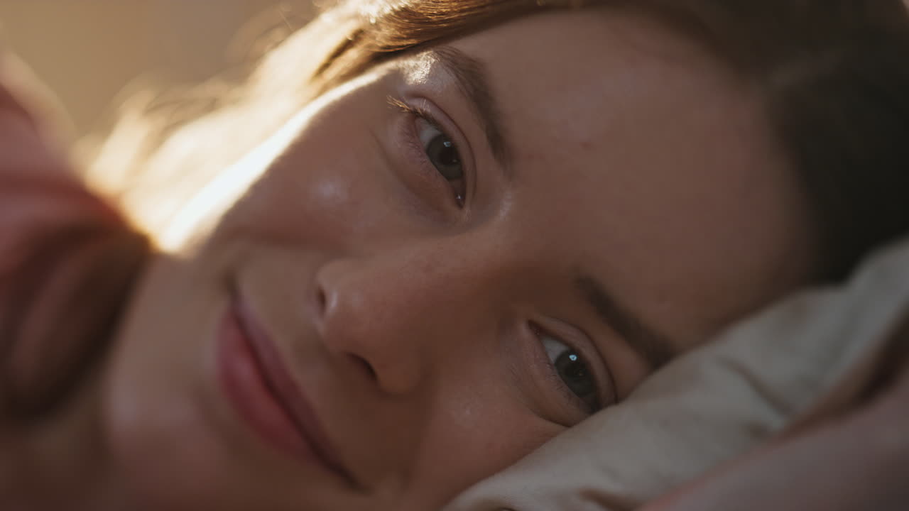 mujer pacífica despertando la luz del sol de la mañana primer plano. feliz chica sonriente ojos abiertos