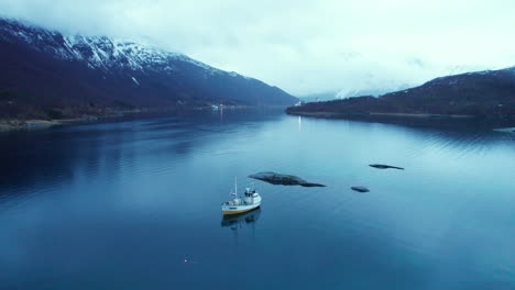 forwarding close up shot of a norwegian fishing boat in a fjord with low clouds around mountains