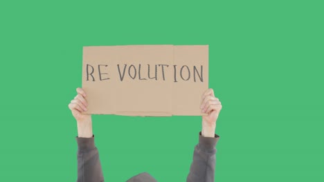 manifestantes con manos sosteniendo una pancarta de cartón con la inscripción de la revolución en fondo verde chromakey. hombre irreconocible mostrando el letrero de la revolución en cartón.