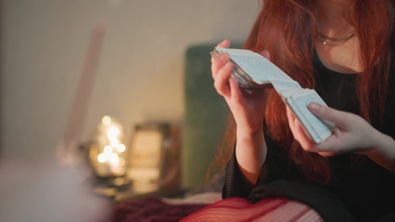 Người phụ nữ da trắng duyên dáng tiết lộ lá bài. Buổi xem bài tarot thân mật được thắp sáng bằng nến với đôi tay chăm chú. Tiết lộ lá bài tarot ấm áp và đầy hy vọng được thực hiện bởi người phụ nữ tóc đỏ dưới ánh nến.