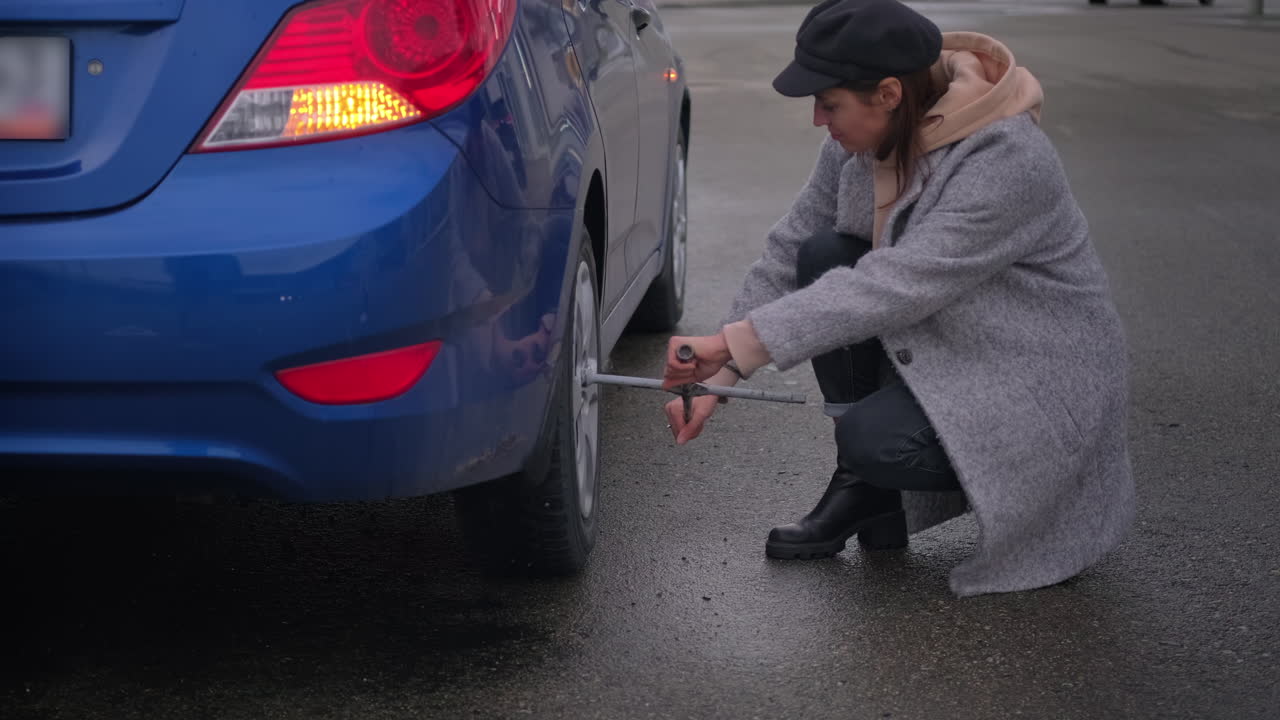 비가 오는 동안 타이어를 바꾸는 여자