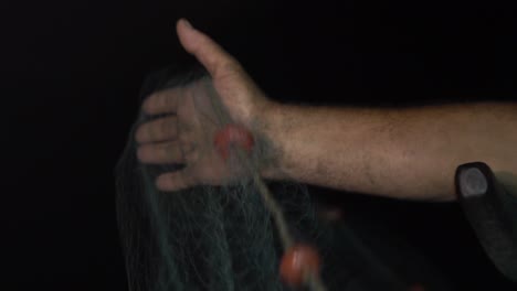 close-up as a fisherman runs a fishnet through his hands when trawling at night