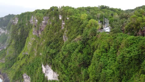 Aerial-panning-view,-Tree-houses-on-tropical-lush-steep-Cliffs,-Nusa-Penida-Island