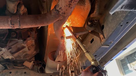 African-man-uses-acetylene-cutting-torch-on-auto-exhaust-mount-in-shop