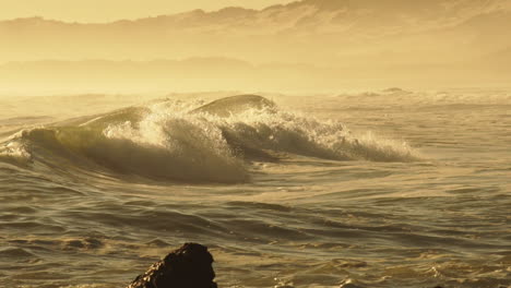 des vagues violentes s'écrasent sur le rivage rocheux pendant l'après-midi doré.