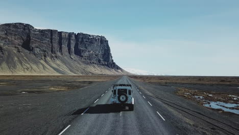 Aerial-View-of-a-four-wheel-drive-driving-on-empty-street-in-beautiful-scenery-in-Iceland
