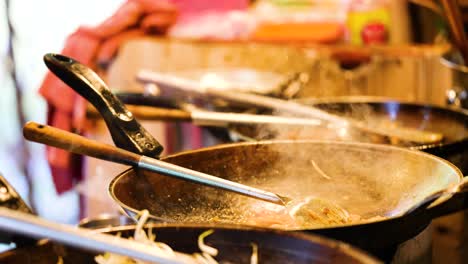 chef prepares pad thai at bustling market stall