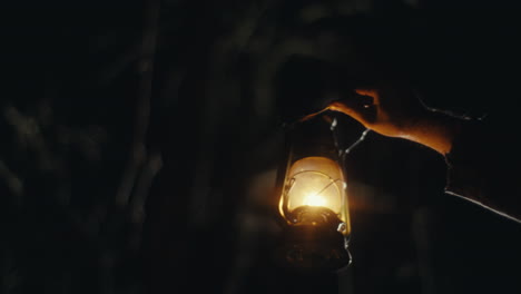 hand holding a lit lantern in the dark
