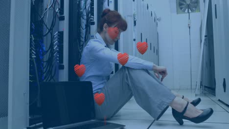 Animation-of-hearts-over-caucasian-businesswoman-in-server-room