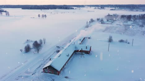 Bauernhaus-Aus-Rotem-Backstein,-Das-Bei-Schneefall-Mit-Schnee-Bedeckt-Ist,-Mit-Rauchendem-Schornstein-Während-Der-Heizperiode