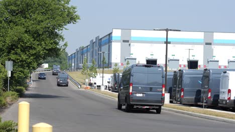 Camionetas-De-Amazon-Conducen-En-El-Estacionamiento-Del-Almacén-De-Amazon-En-Dirección-Al-Almacén-Para-Comenzar-Las-Entregas-Del-Día.