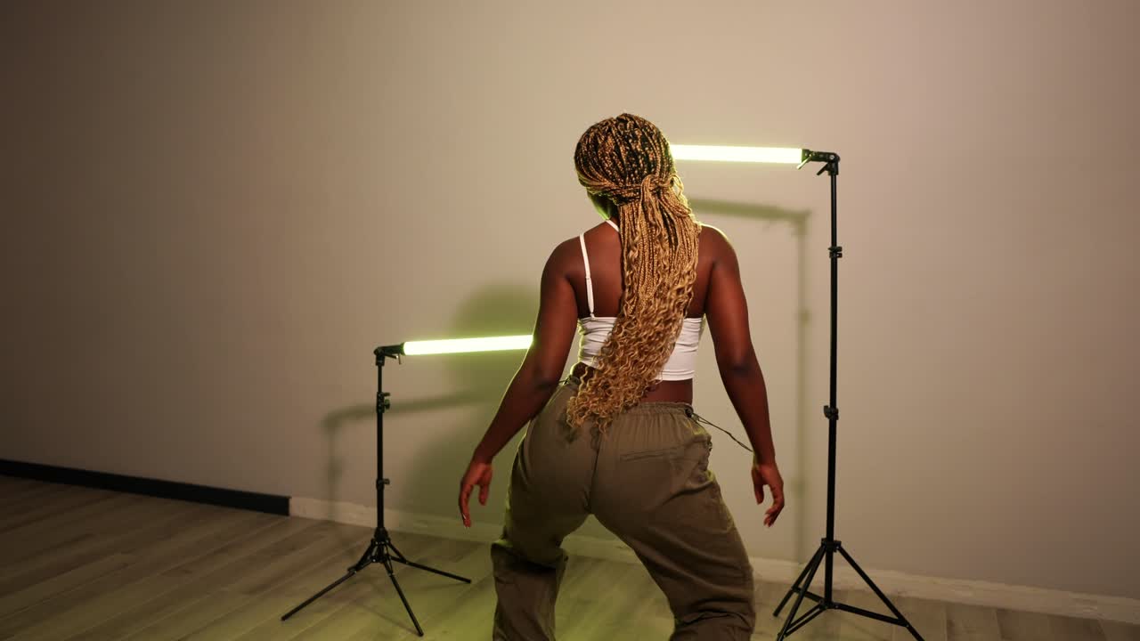 Femme dansant avec des tresses sous un éclairage de studio