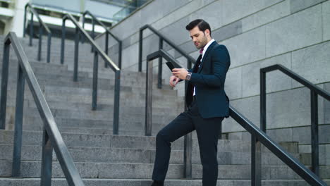 businessman laughing with phone in hand at street. man using smartphone outdoor