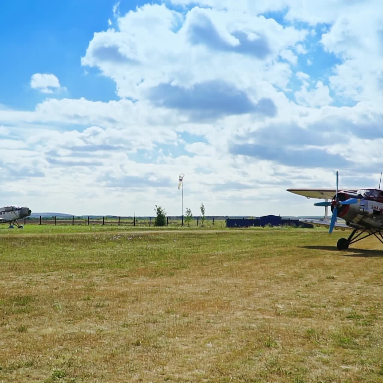 Plane riding circles by the grassy land. Little rural airport. Beautiful blue skies with white clouds at backdrop