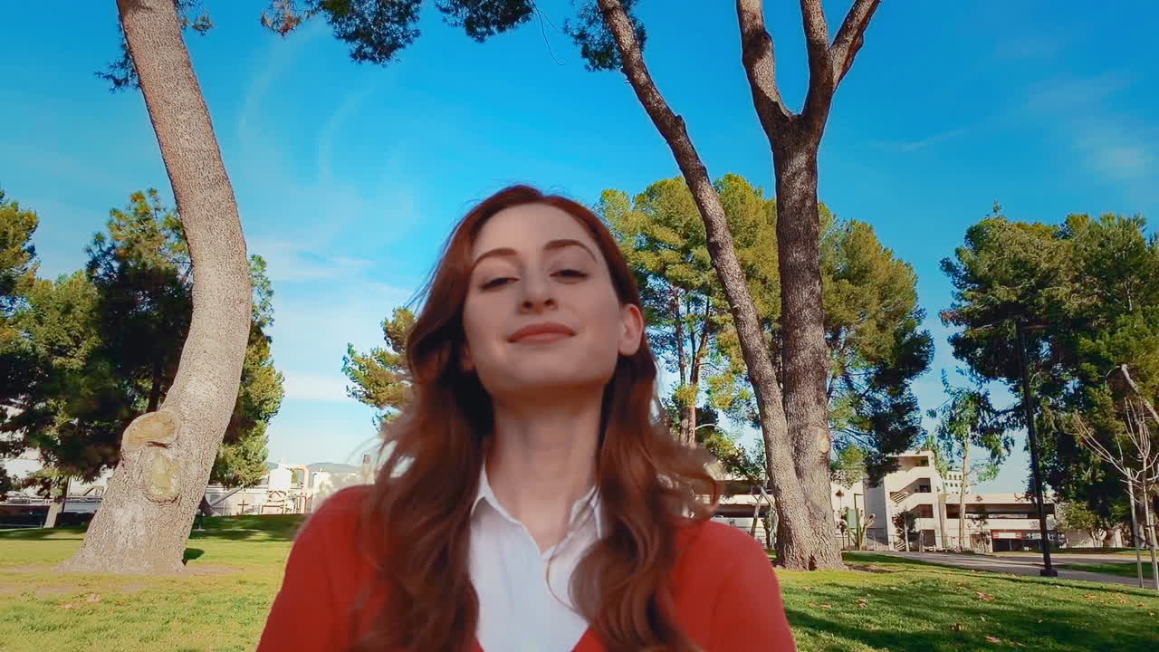 una feliz, atractiva, joven, mujer caucásica en el parque mirando a la cámara con una mirada de orgullo y contenido