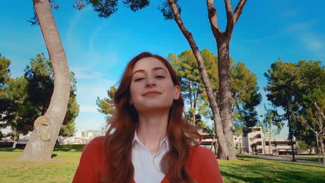 una feliz, atractiva, joven, mujer caucásica en el parque mirando a la cámara con una mirada de orgullo y contenido