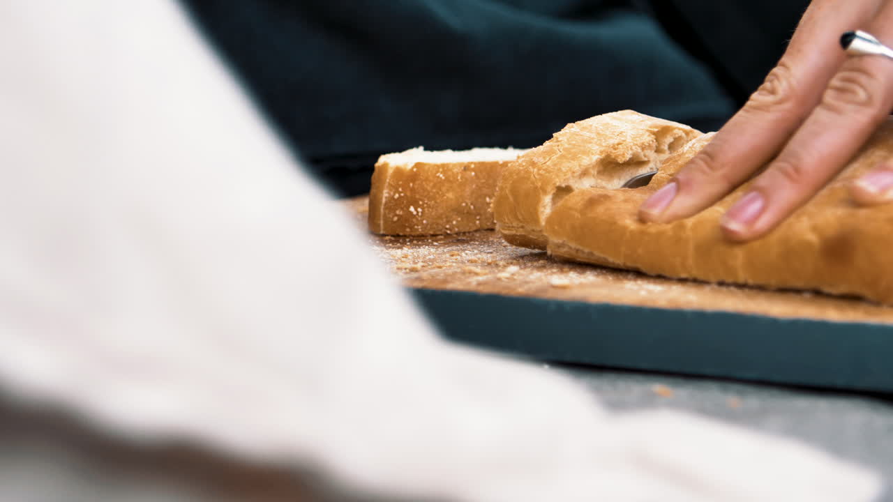 Woman cutting delicious baguette on a bread board