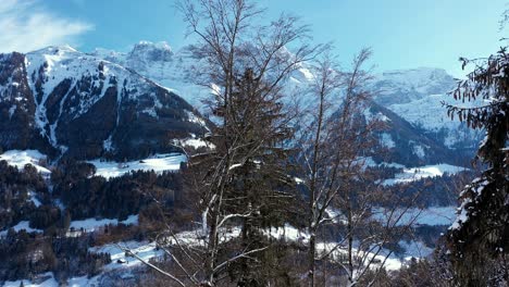 Amazing-drone-flight-of-a-stunning-alpine-valley,-village-and-snow-covered-mountain-peaks-in-Champery,-Switzerland