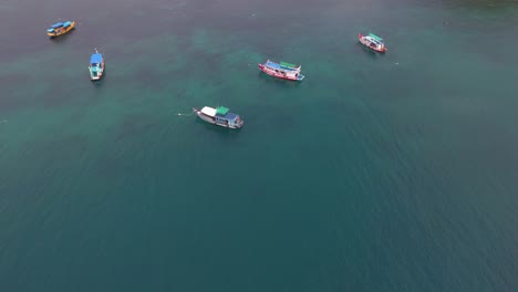 aerial view of boats anchored in turquoise waters off a tropical island