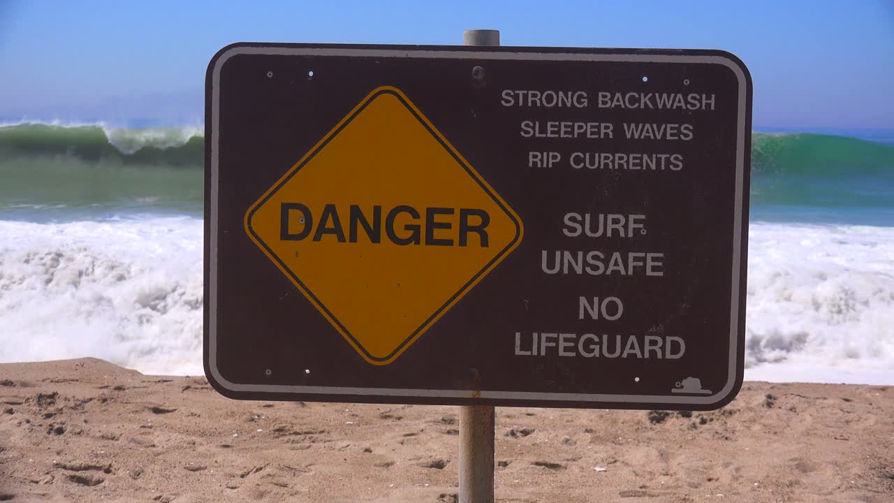 знак на калифорнийском пляже предупреждает об опасном прибое и сильных разрывных течениях 1
