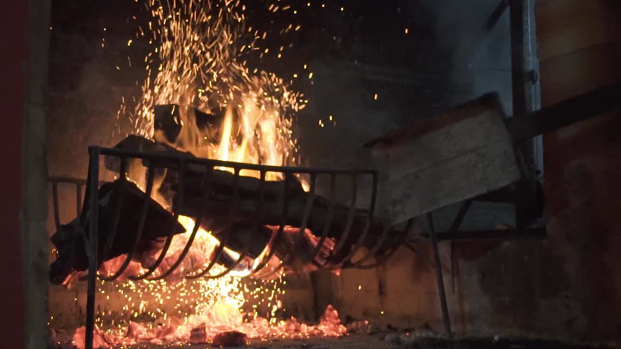 Close shot of the fire, an artisan preparing wood on the side of barbecue grill