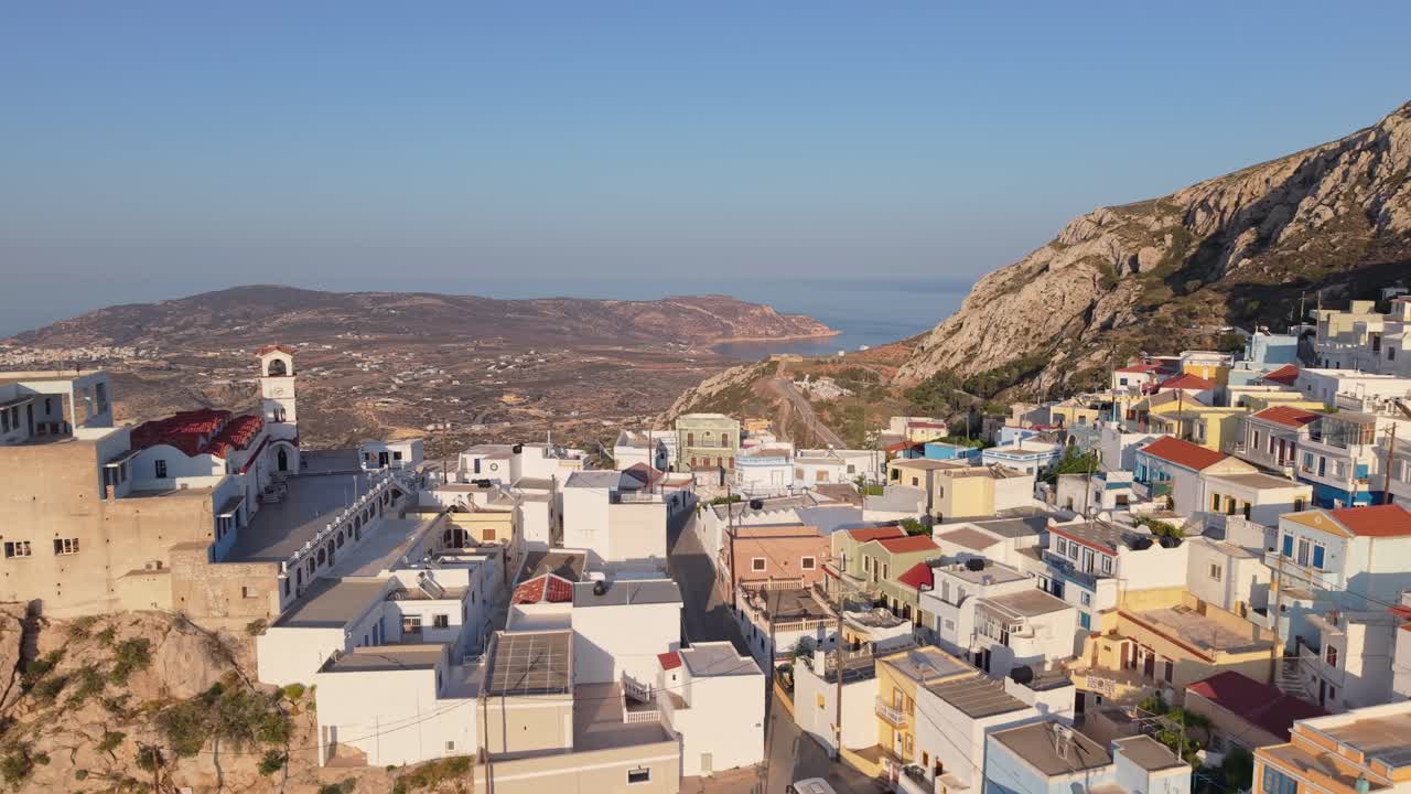 Pull-back drone movement revealing Menetes Village on Karpathos Island, Greece, with scenic mountains and Mediterranean landscape in the background
