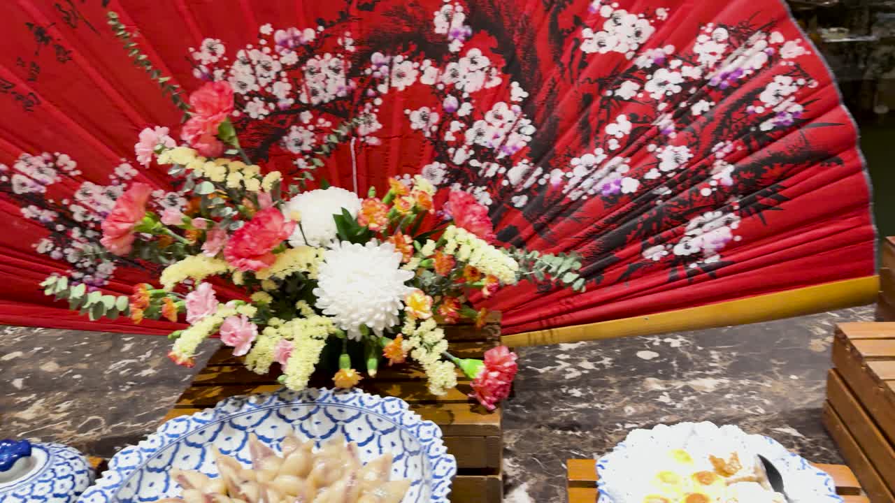 A vibrant dessert buffet with floral decor and traditional Thai elements, captured in warm lighting at a Phuket resort