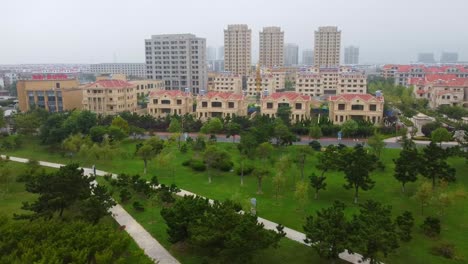 Aerial-view-of-high-rise-cityscape-and-sea-waves-lapping-on-Nanhai-Beach,-China