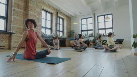 women practicing yoga in a bright studio with brick walls and large windows