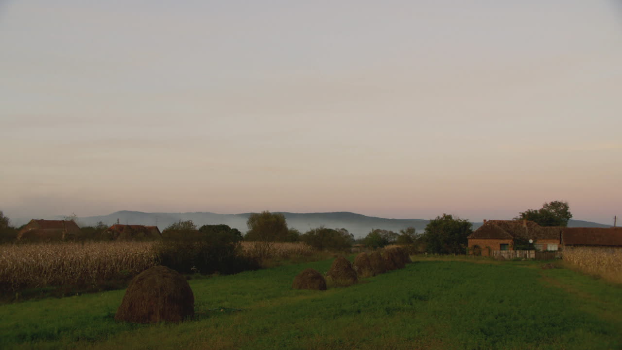 Dusk wide shot of haystacks in Romanian countryside