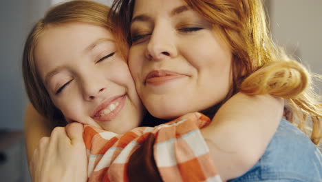 close up of the cute happy girl with her mother hugging and telling each other how much they love each other. portrait shot. indoor