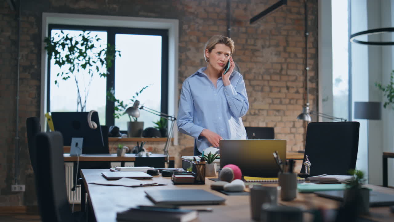 Donna impegnata che parla al cellulare in un ufficio moderno. Seria donna d'affari che telefona.