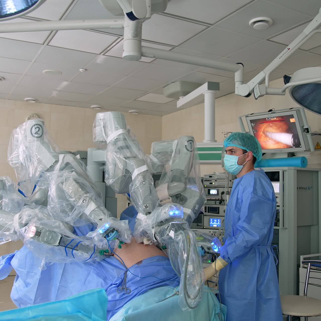 Patient at the surgery table is operated by the advanced technological equipment. Male doctor controlling the procedure standing beside
