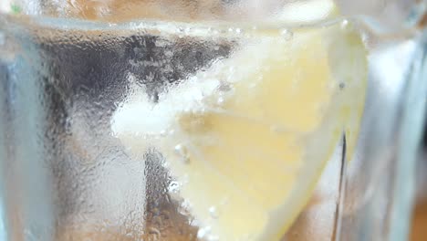 primer plano de una rodaja de limón en un vaso de agua con hielo