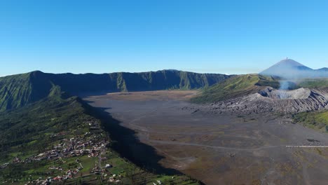 aerial wide shot of mount bromo and mount semeru volcano. cemoro lawang village, east java, indonesia located dangerously on edge of hill. sunny summer day in asia