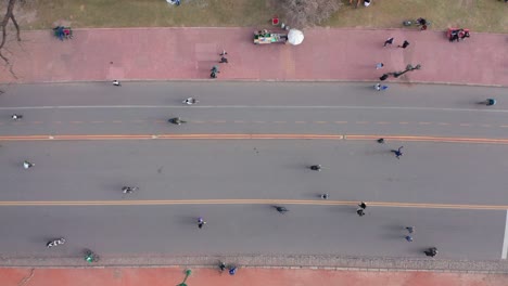 Vertikale-Luftaufnahme-Von-Menschenmassen,-Die-Auf-Einer-Fußgängerzone-Mit-Radweg-Sport-Treiben