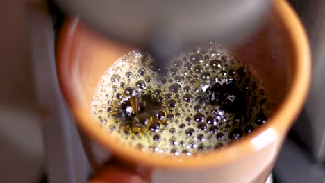 cámara lenta de gotas de café negro goteando de la máquina de café a la taza marrón