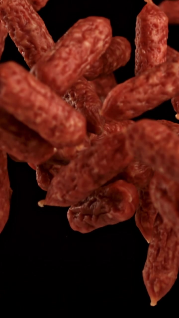 Movimento rallentato di mini salami che cadono su sfondo nero