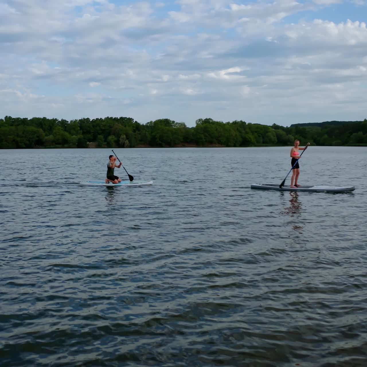Couple on stand up paddle board. Aerial view of people standing on sup board and swims surfing