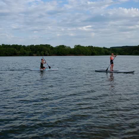 couple on stand up paddle board. aerial view of people standing on sup board and swims surfing