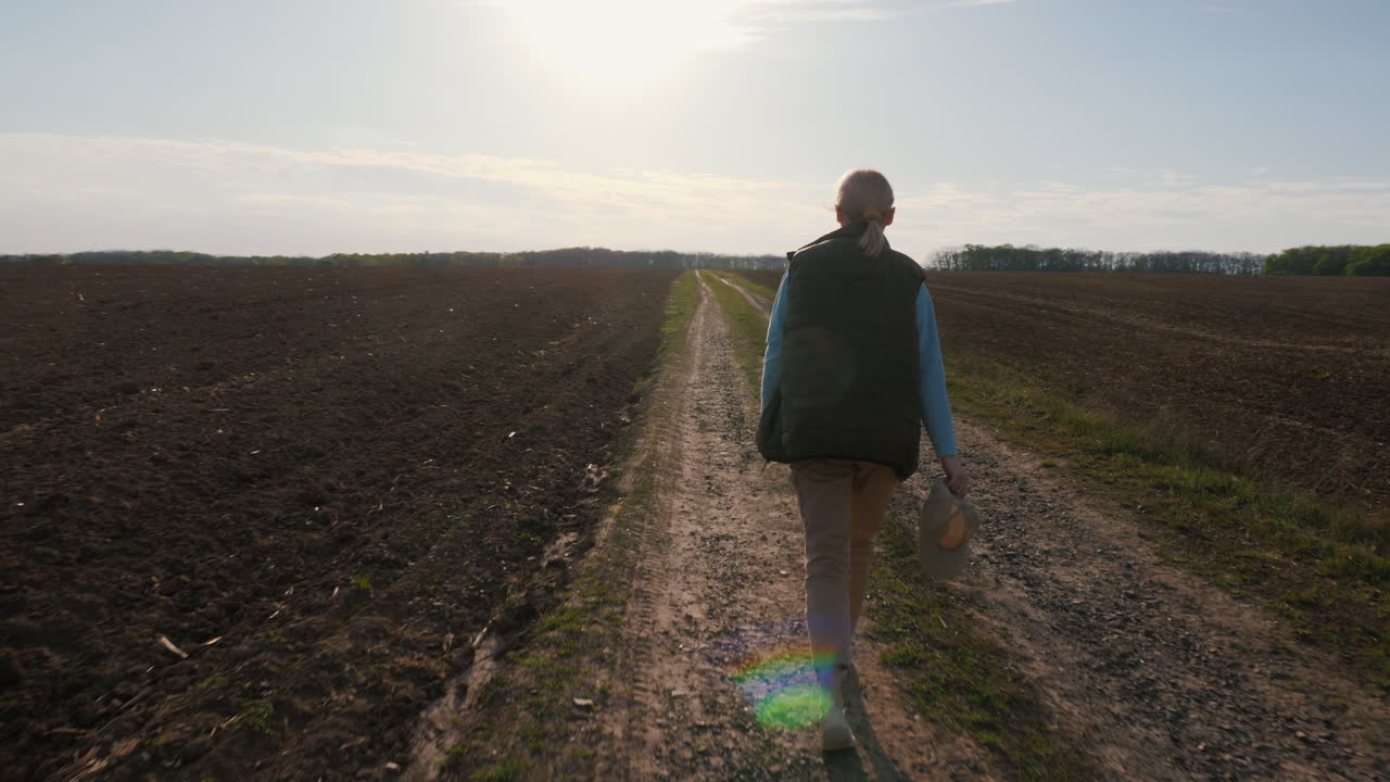 Woman Walking Down a Country Road Through a Field