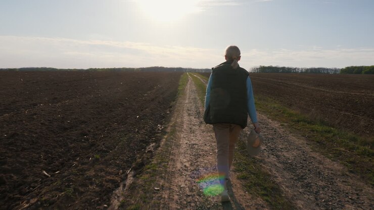 Donna che cammina lungo una strada di campagna attraverso un campo