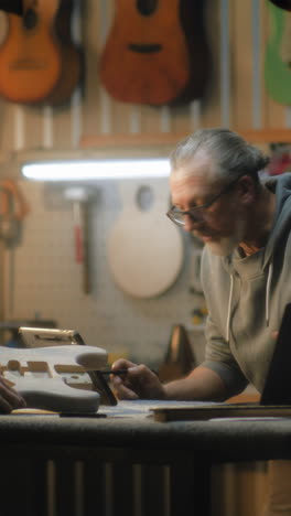 senior craftsman designs guitar in workshop